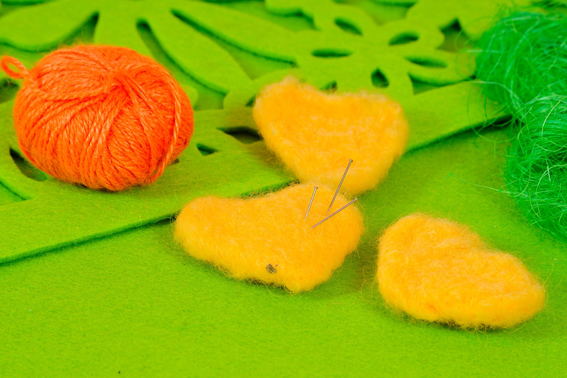 Filzen mit Kindern | gefilzte Herzen gelb, mit grünem Filz und orangem Wollknäuel