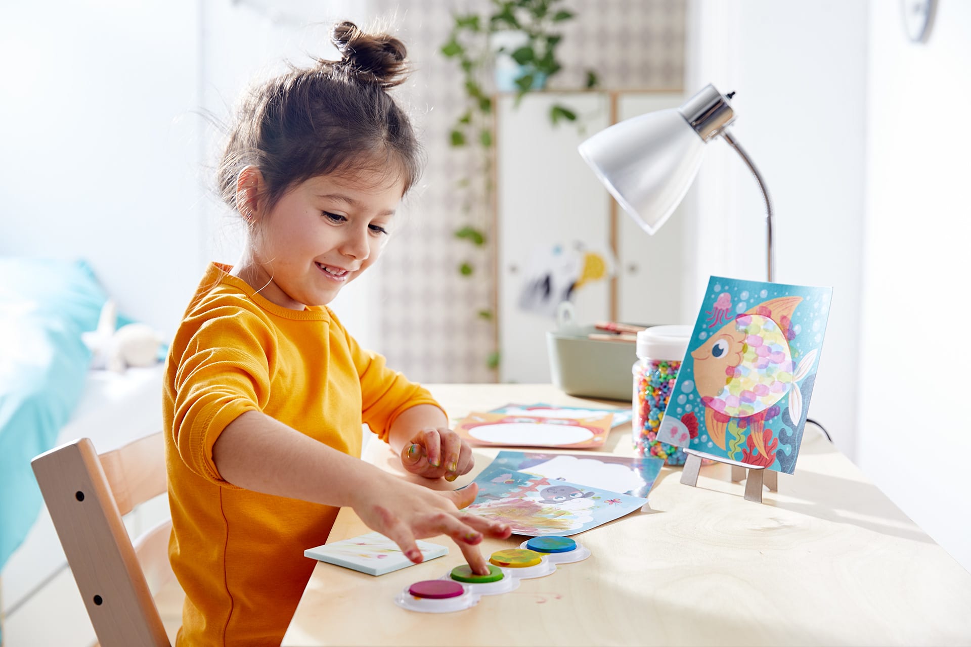  Fingerfarben-Ideen Kinder | Mädchen mit braunen Haaren und gelben Langarmshirt macht Finger in grüner Farbe