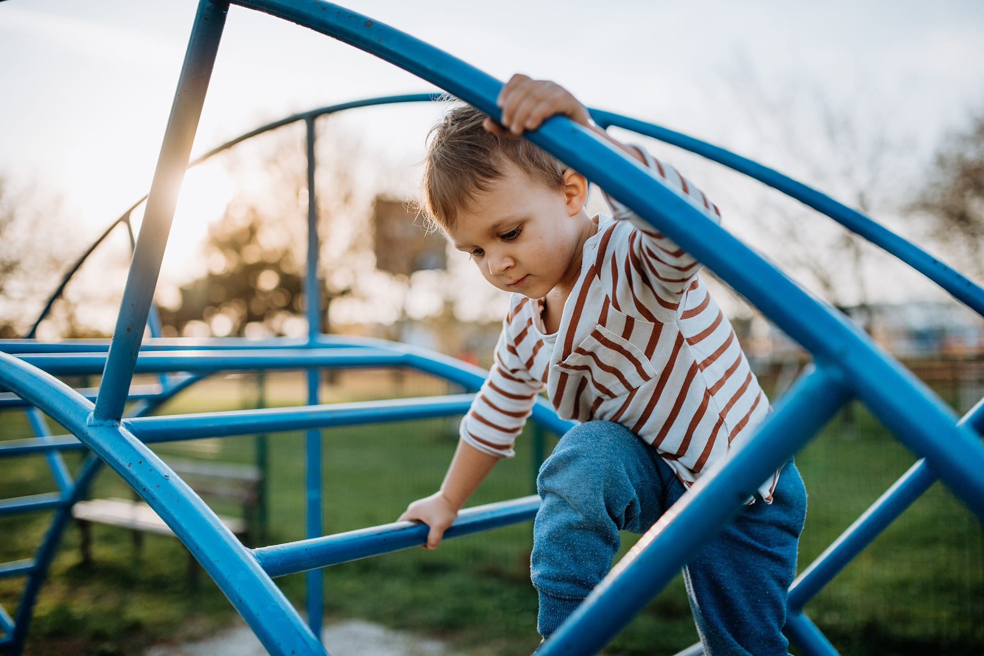  Ganzheitliche Entwicklung Kinder | Ein kleiner Junge spielt auf einem Spielplatz im Freien