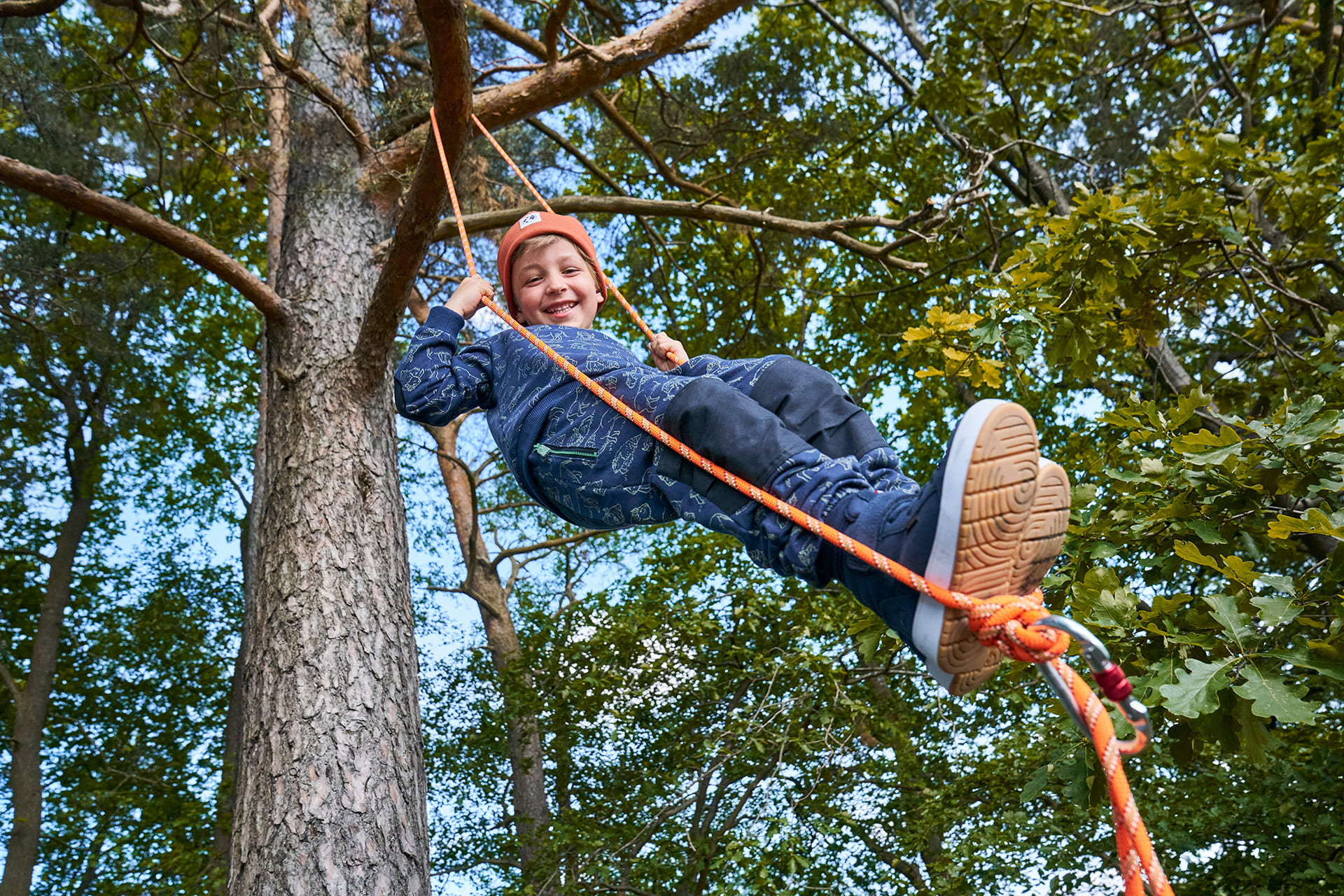 Spiele für draußen | Junge Schaukelt auf einem am Baum befestigten Seil.