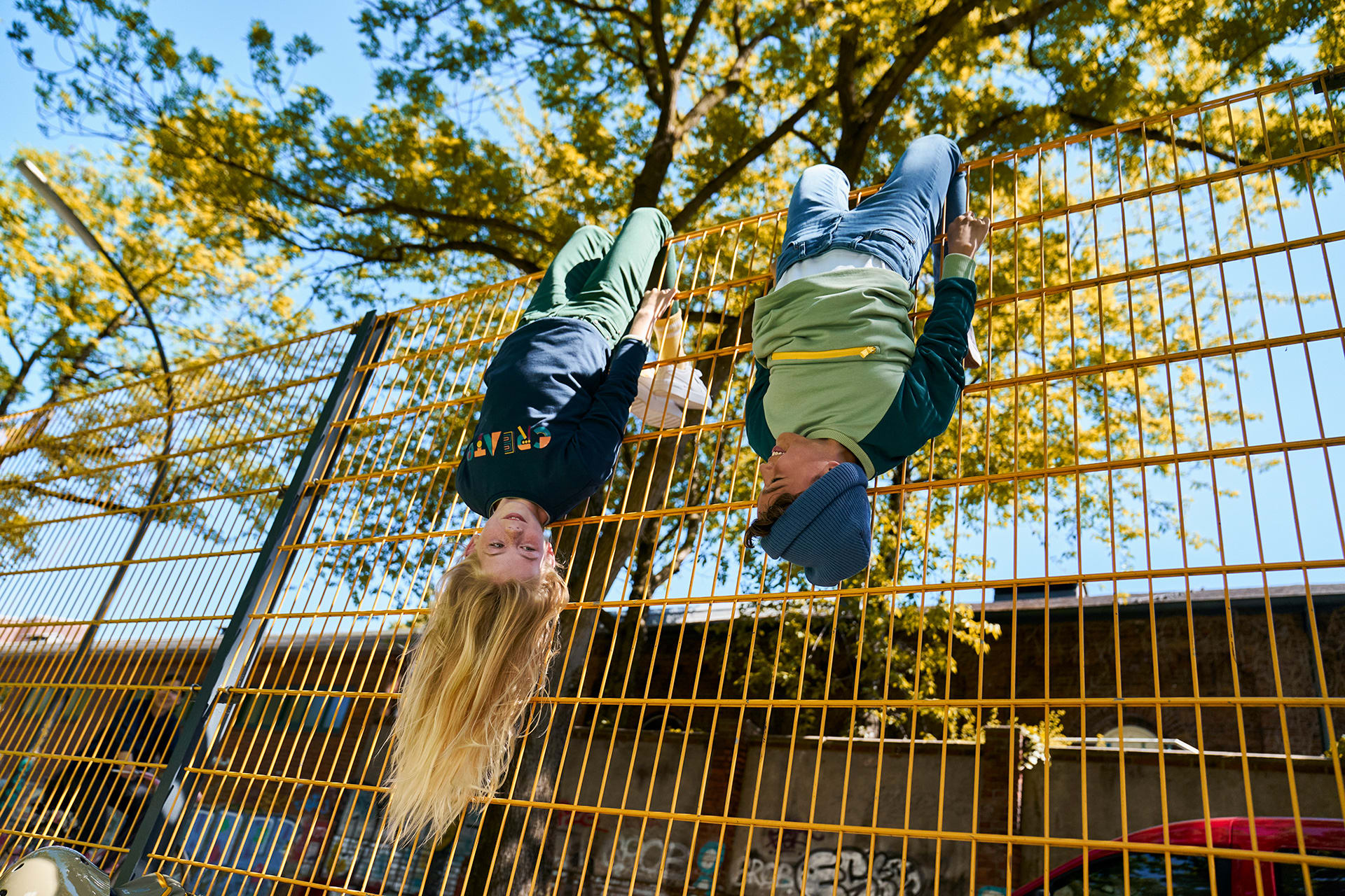 Glückliche Kindheit | Kinder hängen kopfüber am Gartenzaun ab