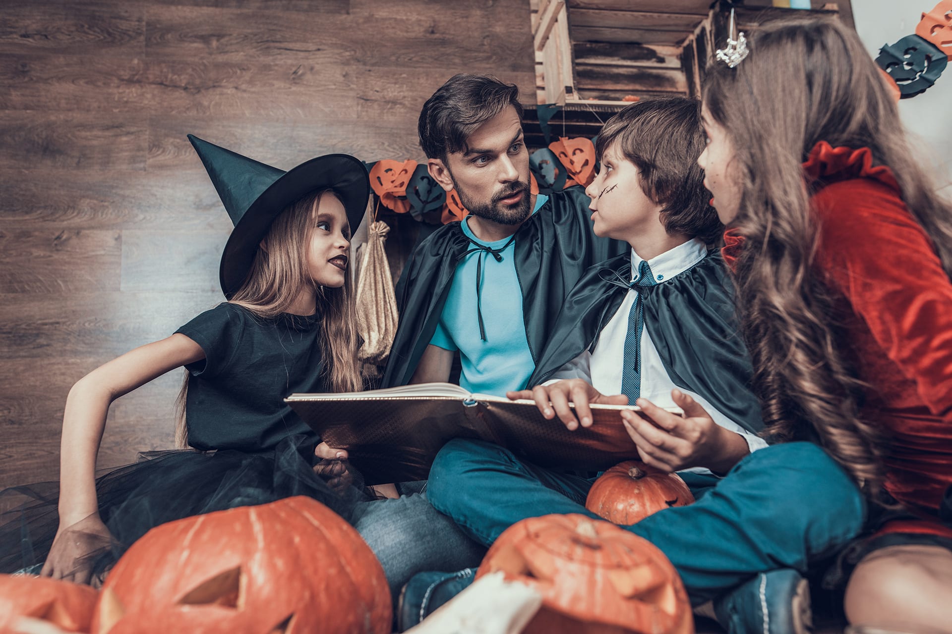 Halloween mit Kindern | Vater schaut sich Buch an mit Kindern in Halloween Kostümen
