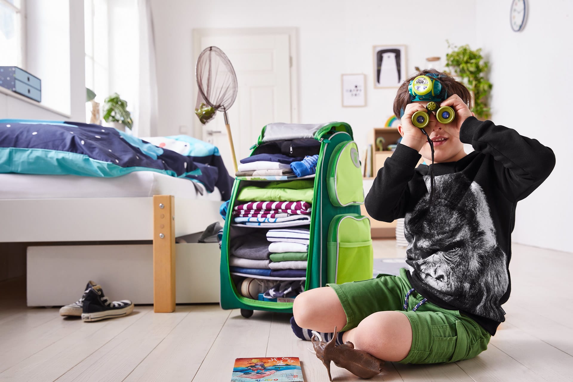 Kinderzimmer gestalten | Junge am Boden mit Fernglas und Trolley im Hintergrund