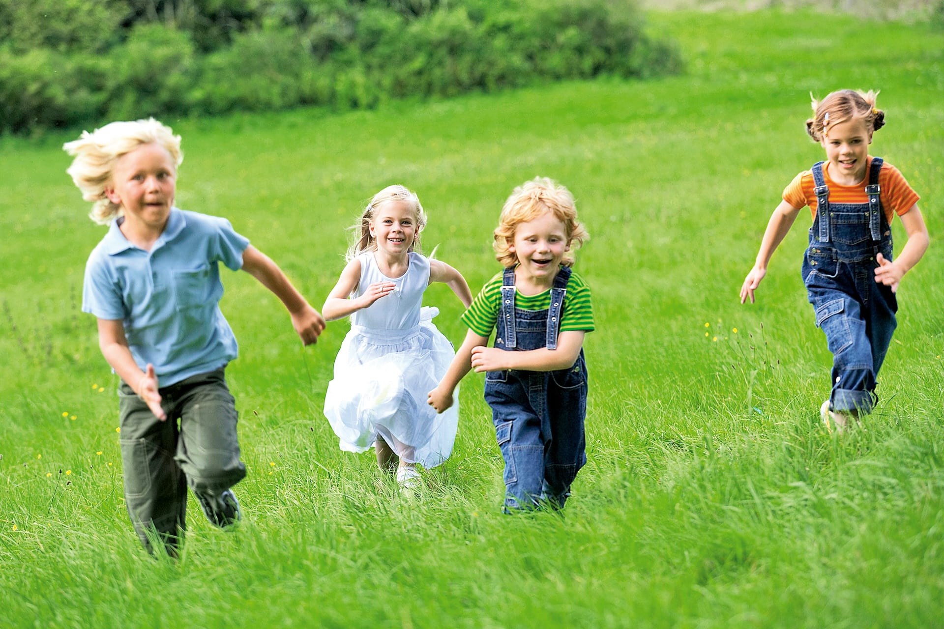 Kind sein | Vier Kinder rennen auf einer Wiese