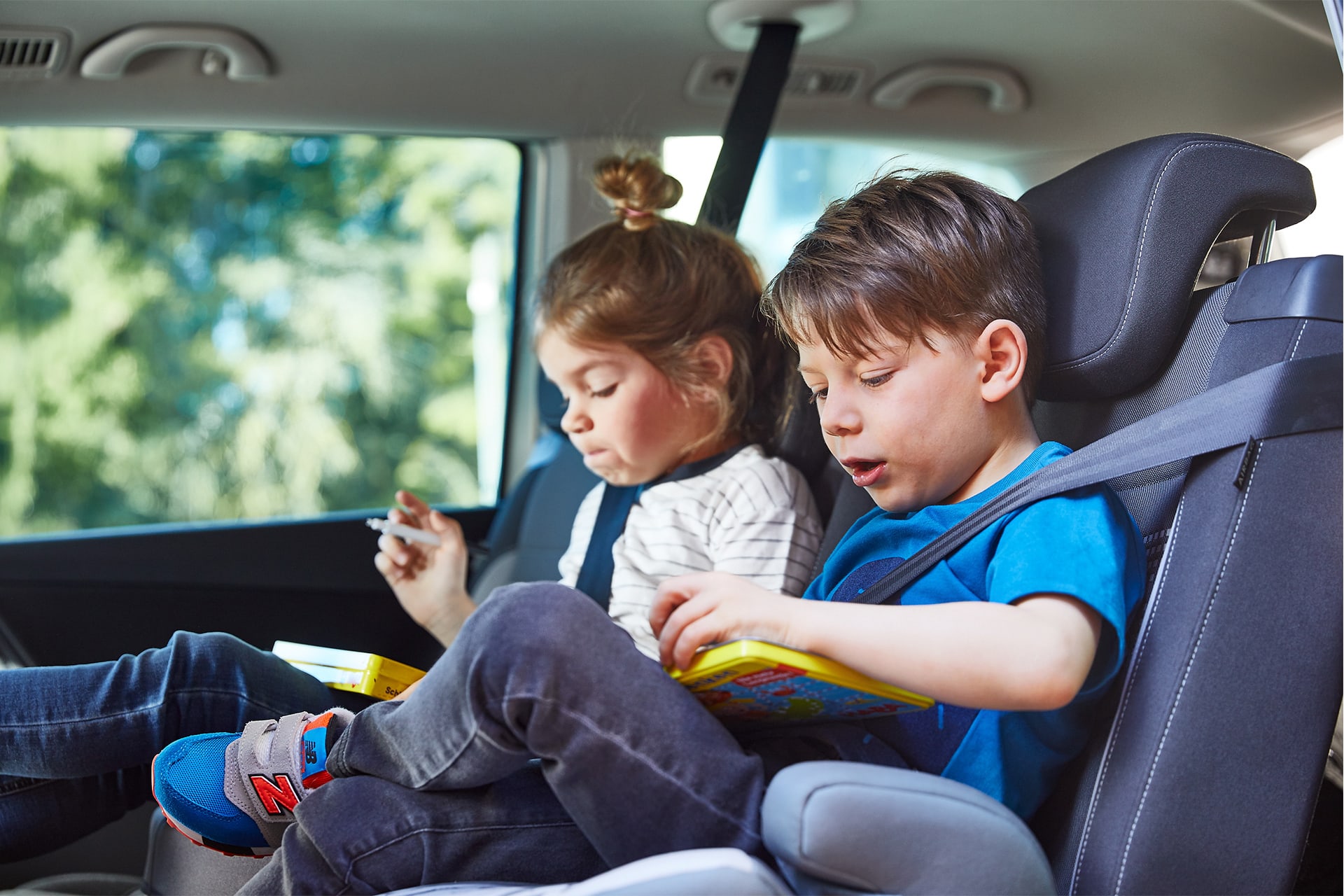 Entspannt Auto fahren mit Kindern | Junge und Mädchen mit braunen Haaren sitzen angeschnallt im Auto 