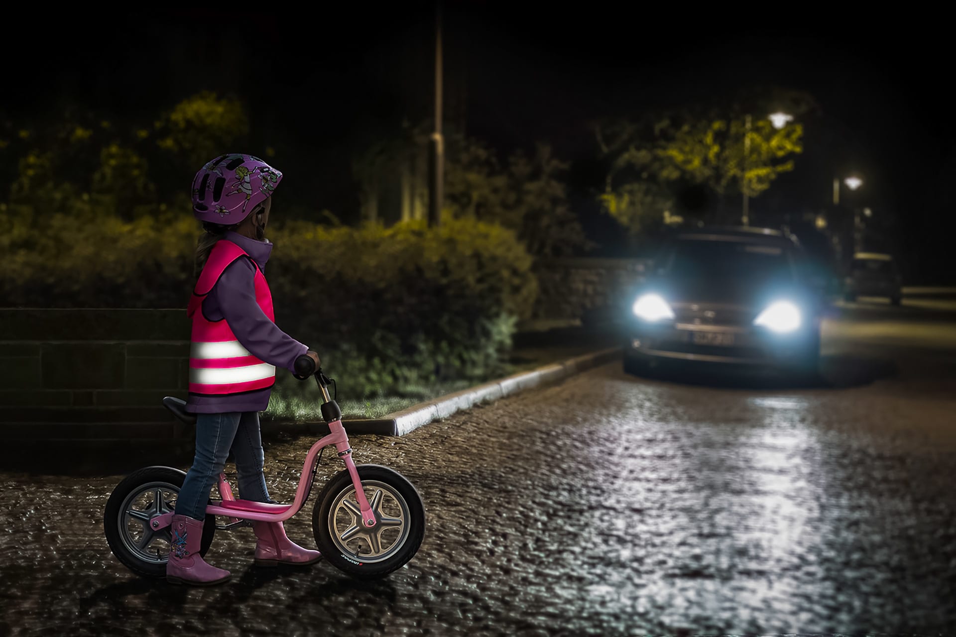 Reflektoren für Kinder | Kind mit Warnweste auf Fahrrad im Dunkeln