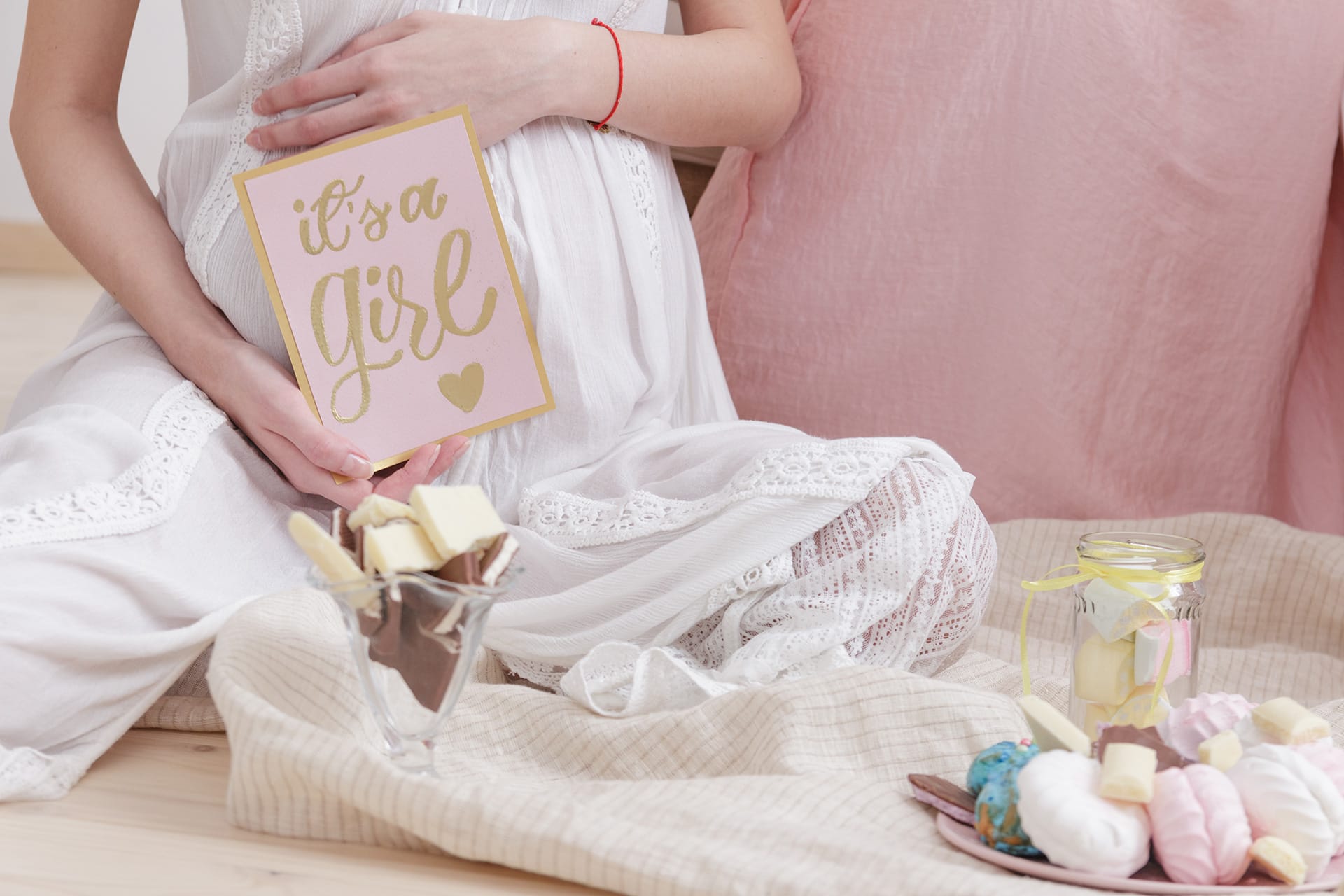  Schwangerschaft verkünden | Schwangerschaft Frau in weißem Kleid sitzt auf dem Boden bei der Feier Baby-Dusche party