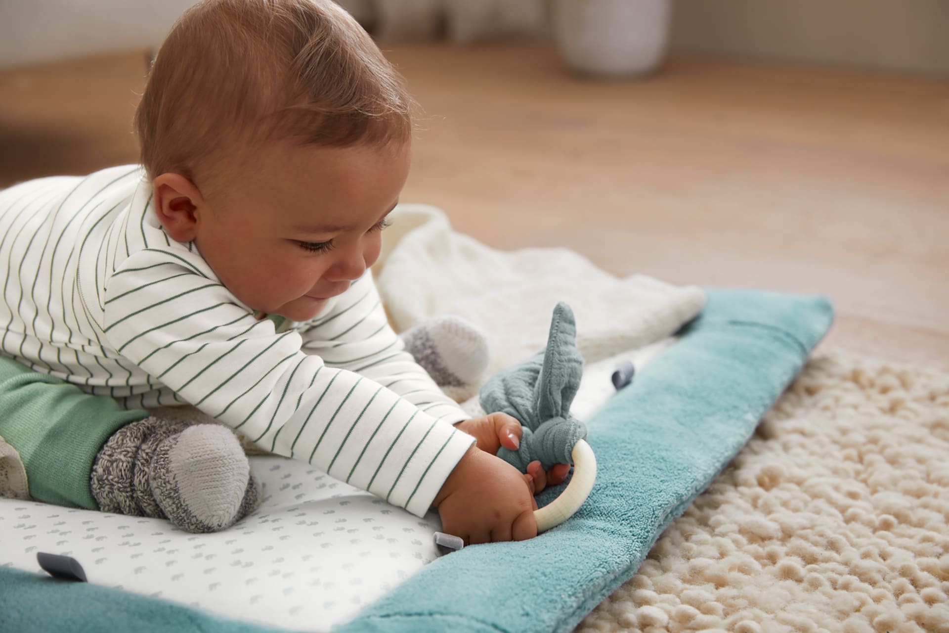 Warum Spielen wichtig ist | dunkelhäutiges Baby sitzt auf Spieldecke