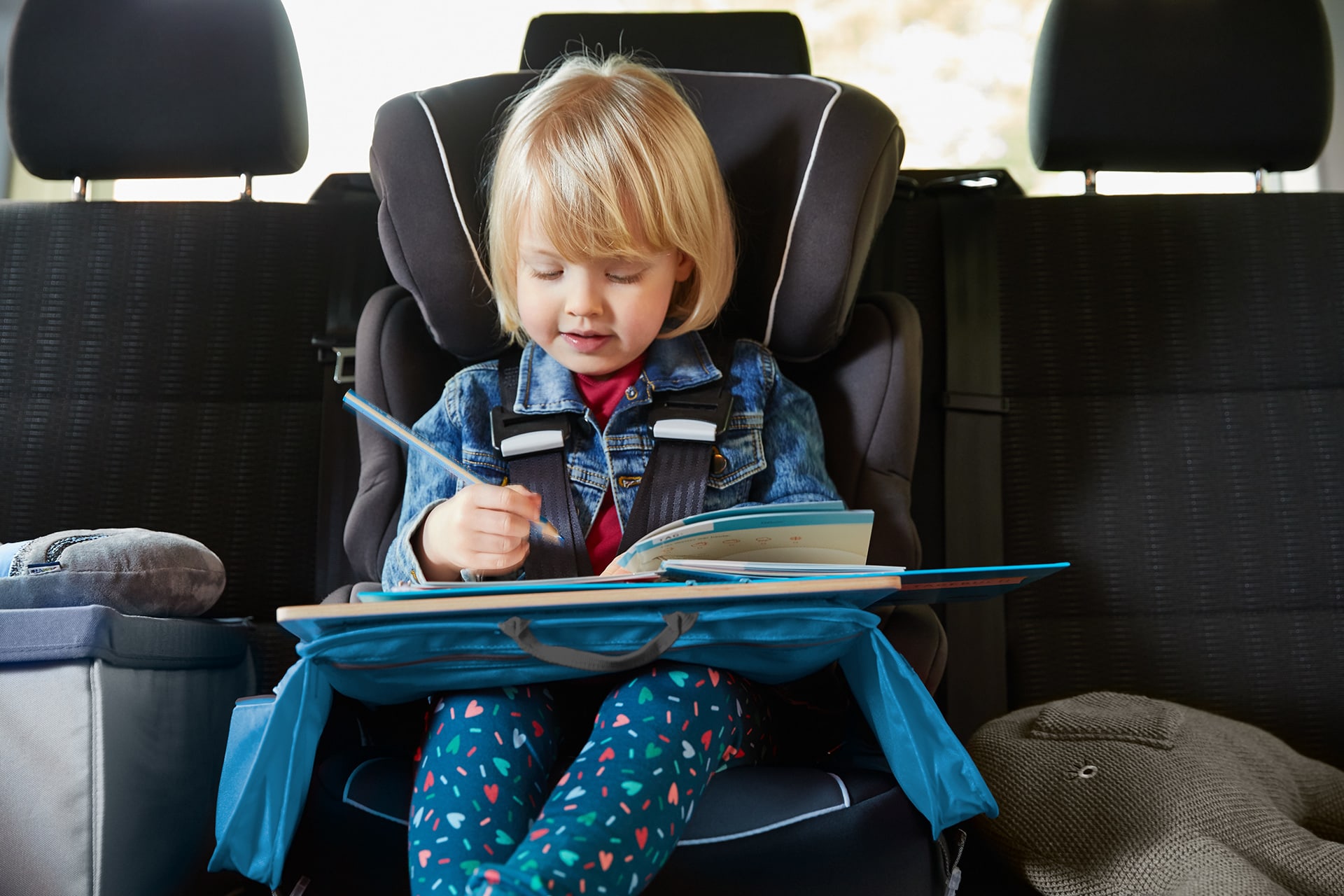 Spielen mit Kindern | Mädchen sitzt im Auto und malt 
