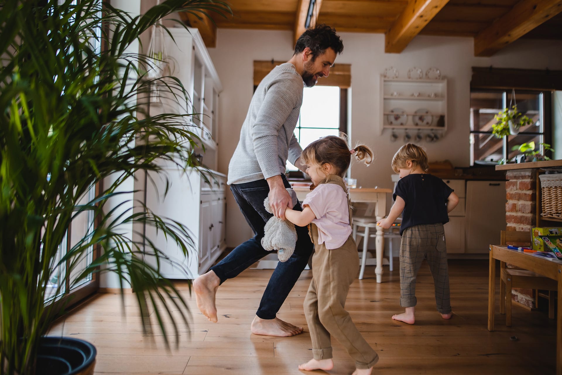 Entspannungsübungen für Kinder | Vater mit zwei kleinen Kindern tanzt zu Hause