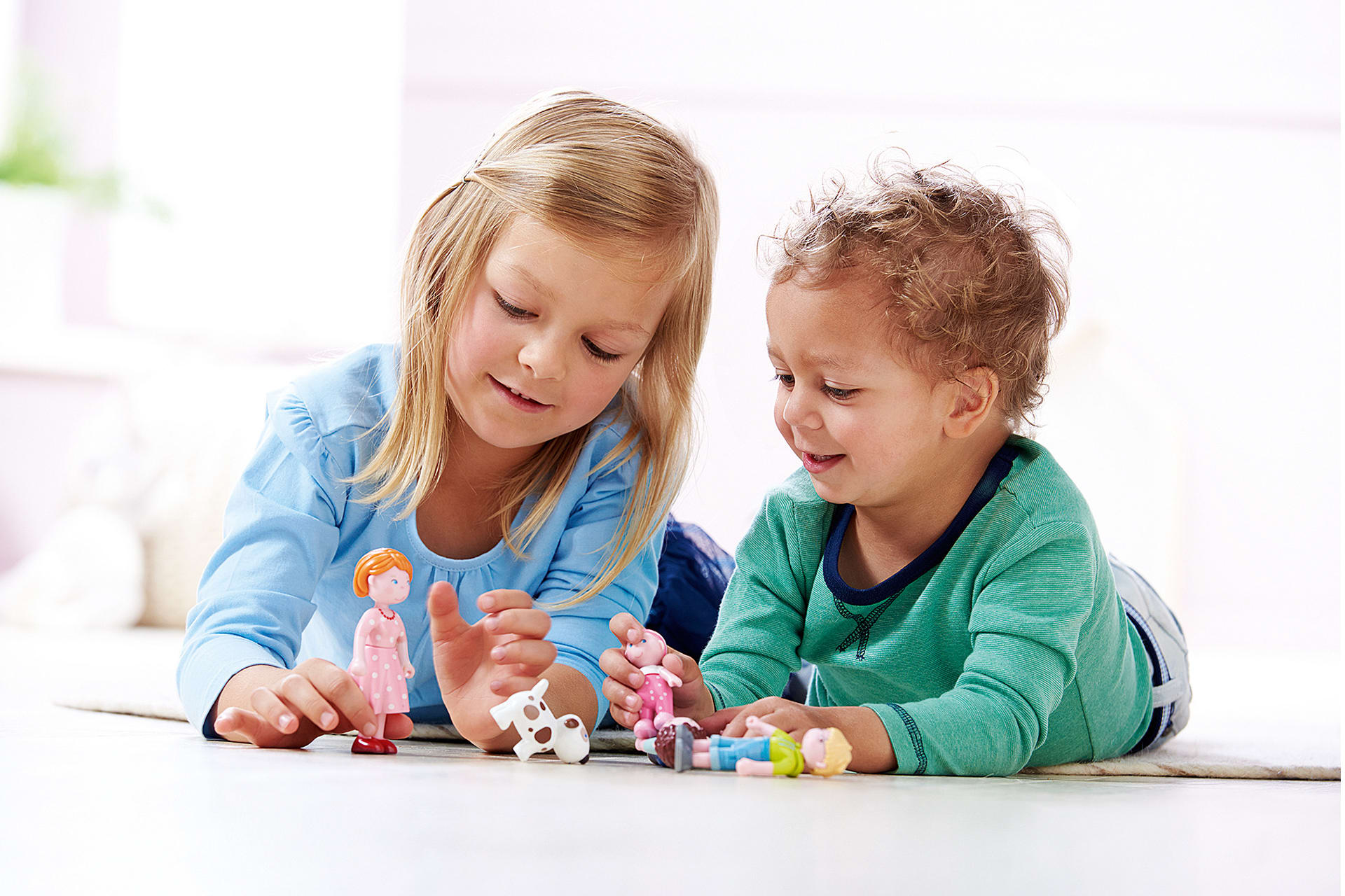 Spielerische Sprachförderung von Kindern | Geschwister liegen auf dem Bauch und spielen mit Little Friends 