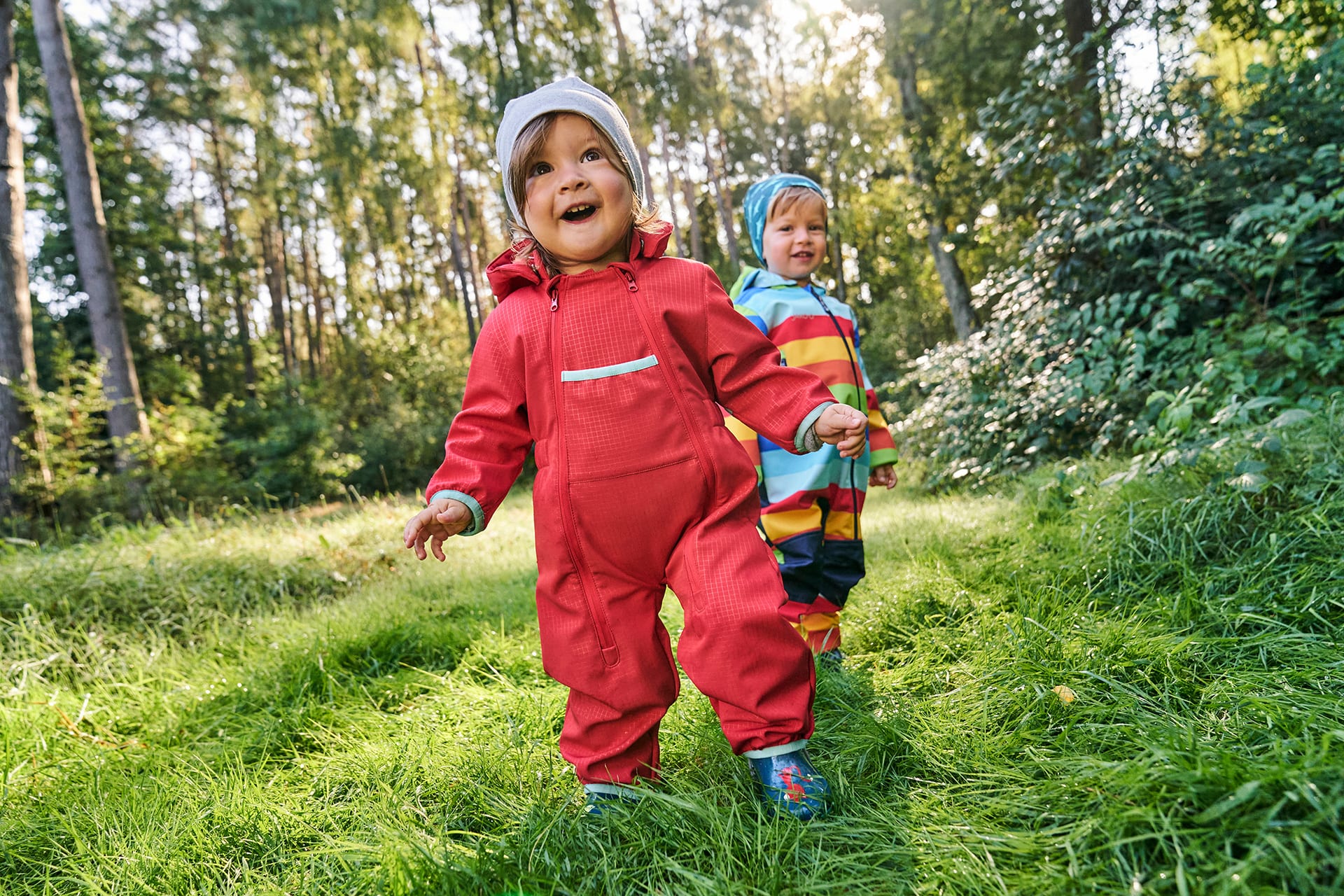 Unternehmungen mit Kleinkind | Zwei Kleinkinder laufen strahlend durch den Wald