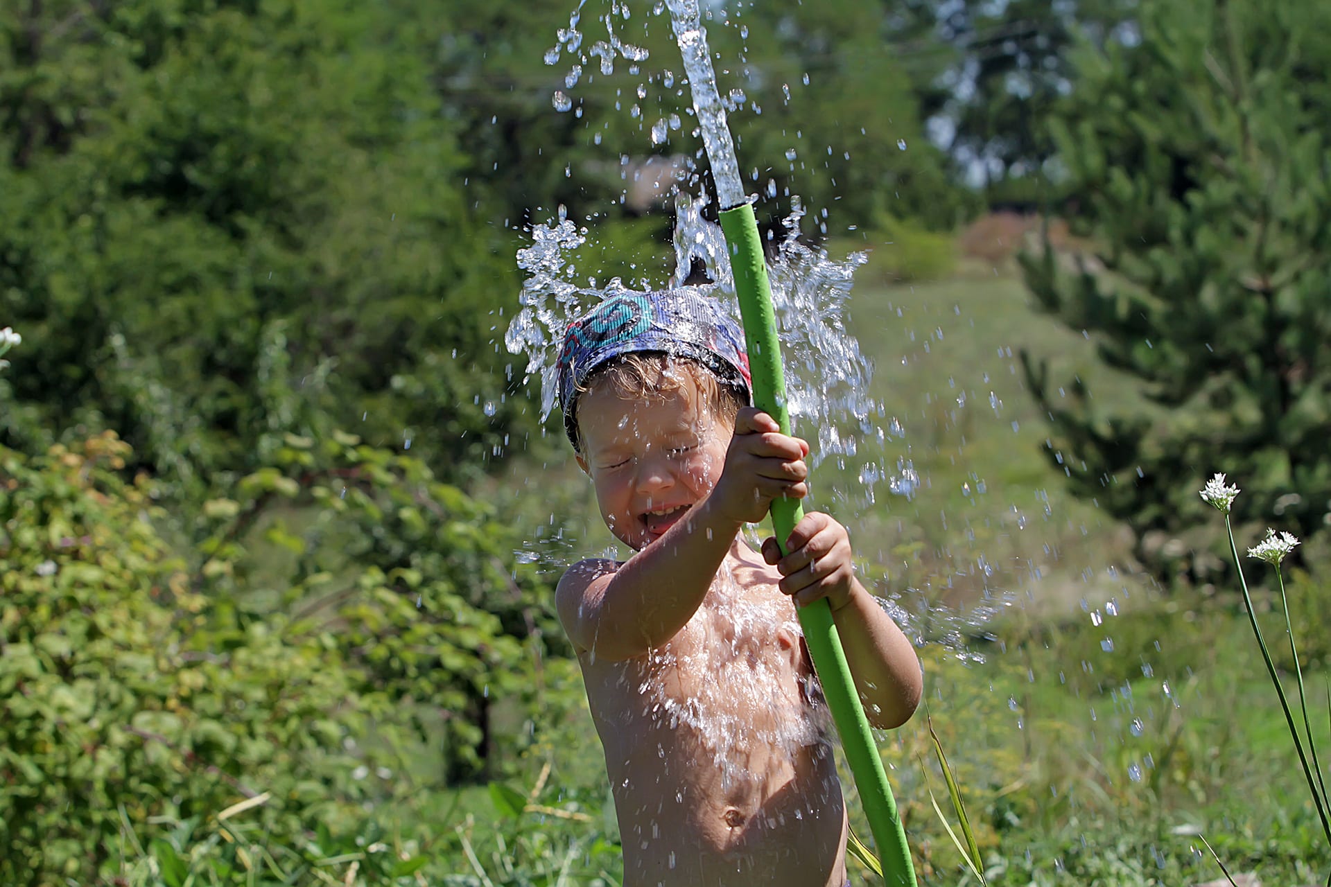 Wasserspiele draußen | Kind spielt mit Gartenschlauch 