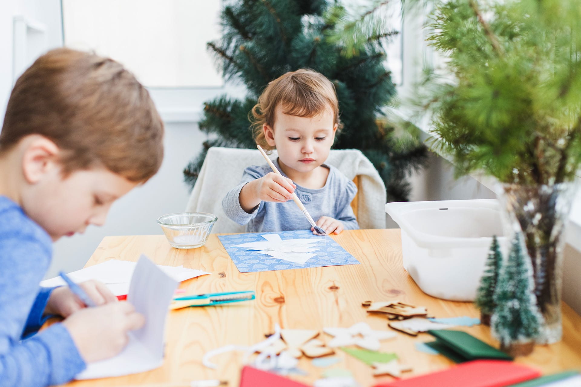 Basteln mit Kindern | Zwei Kinder malen und basteln Weihnachtskarten am Tisch