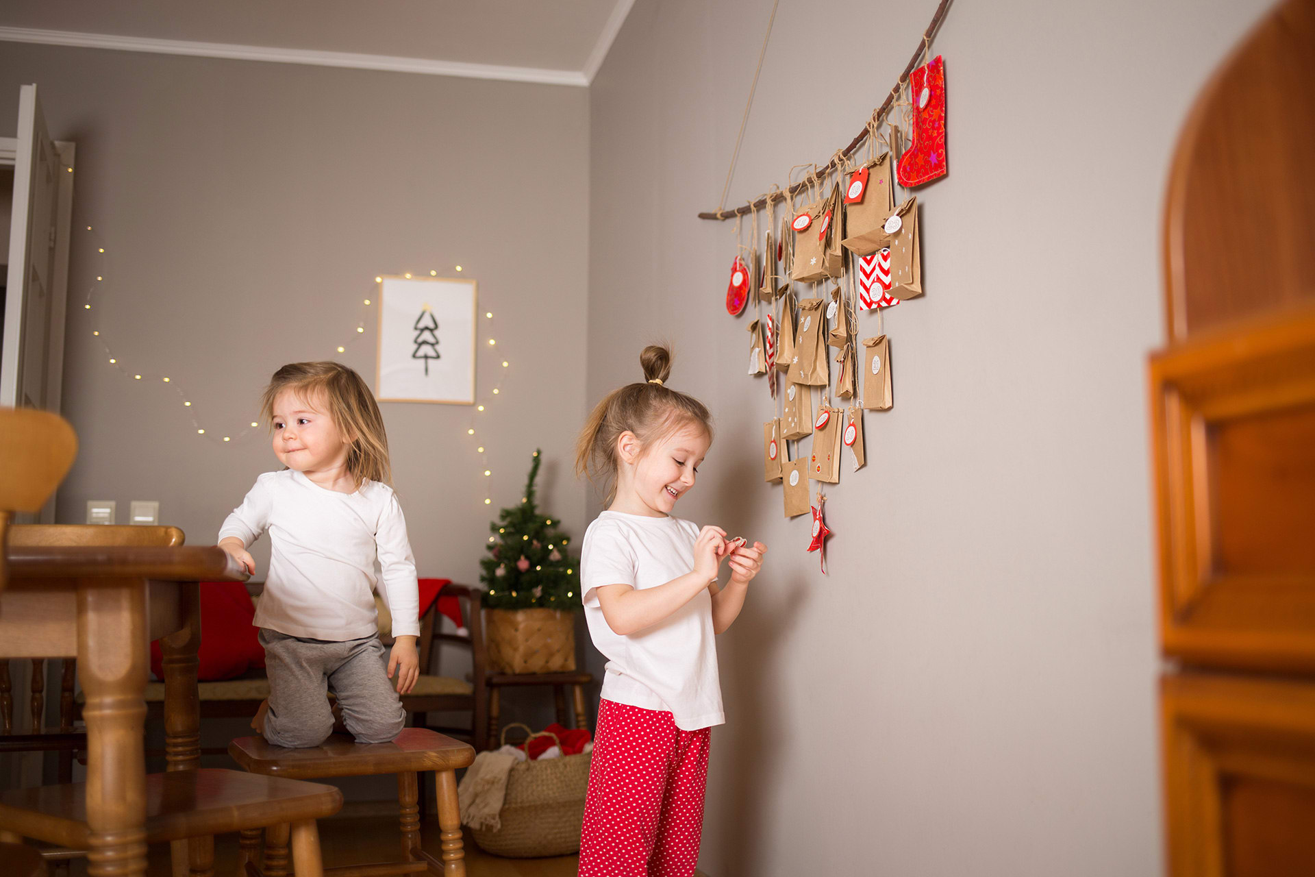 Adventskalender basteln | Schwestern sitzen im Wohnzimmer und gucken sich den Adventskalender an