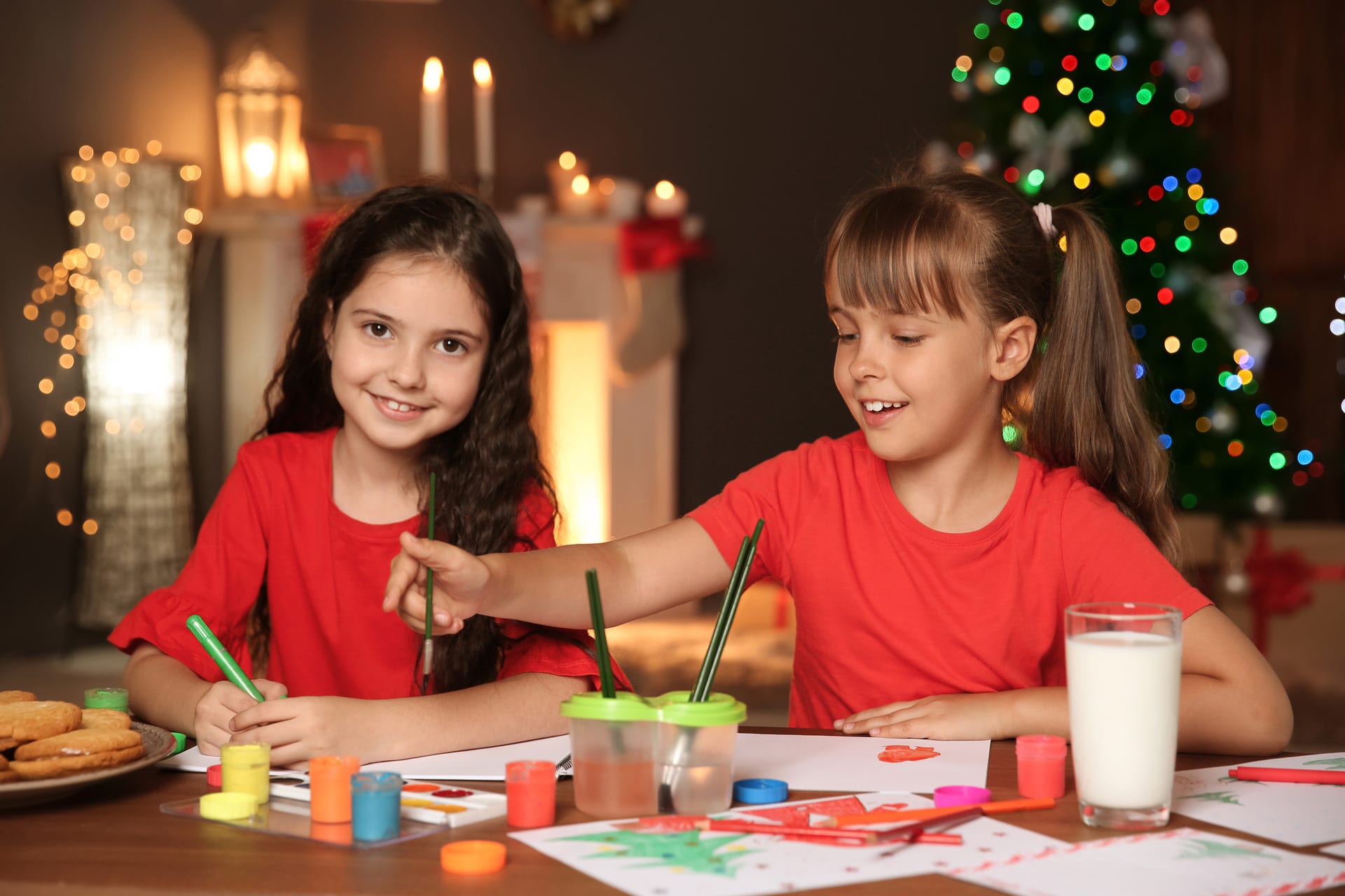 Weihnachtsdeko basteln | Zwei Mädchen malen mit Pinseln auf Papier