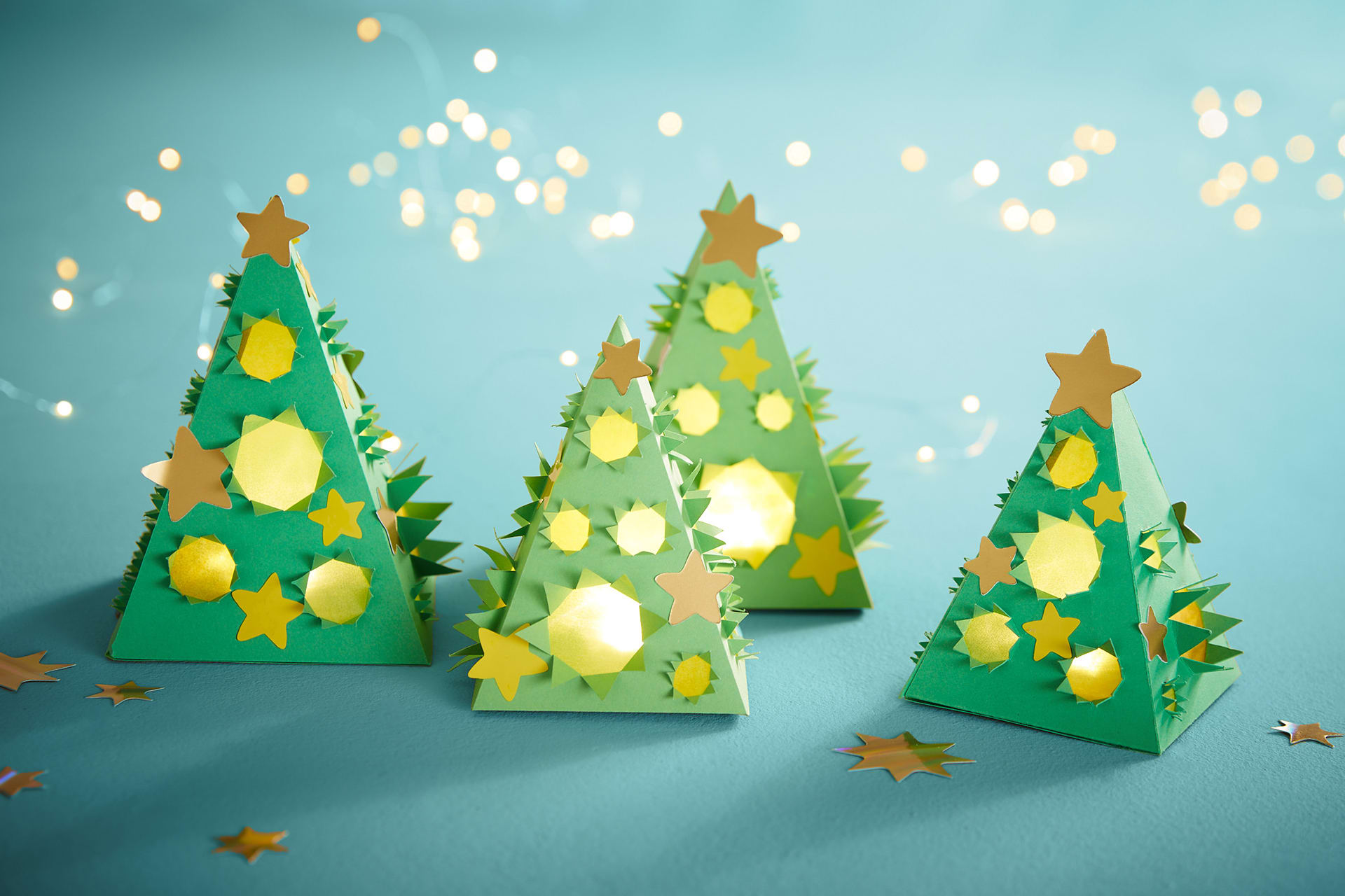 Mal- und Bastelvorlagen | Image | Tannenbäume aus grünem Tonkarton in Pyramidenform,  mit goldenen Sternen, Lichtlöcher mit Transparent
