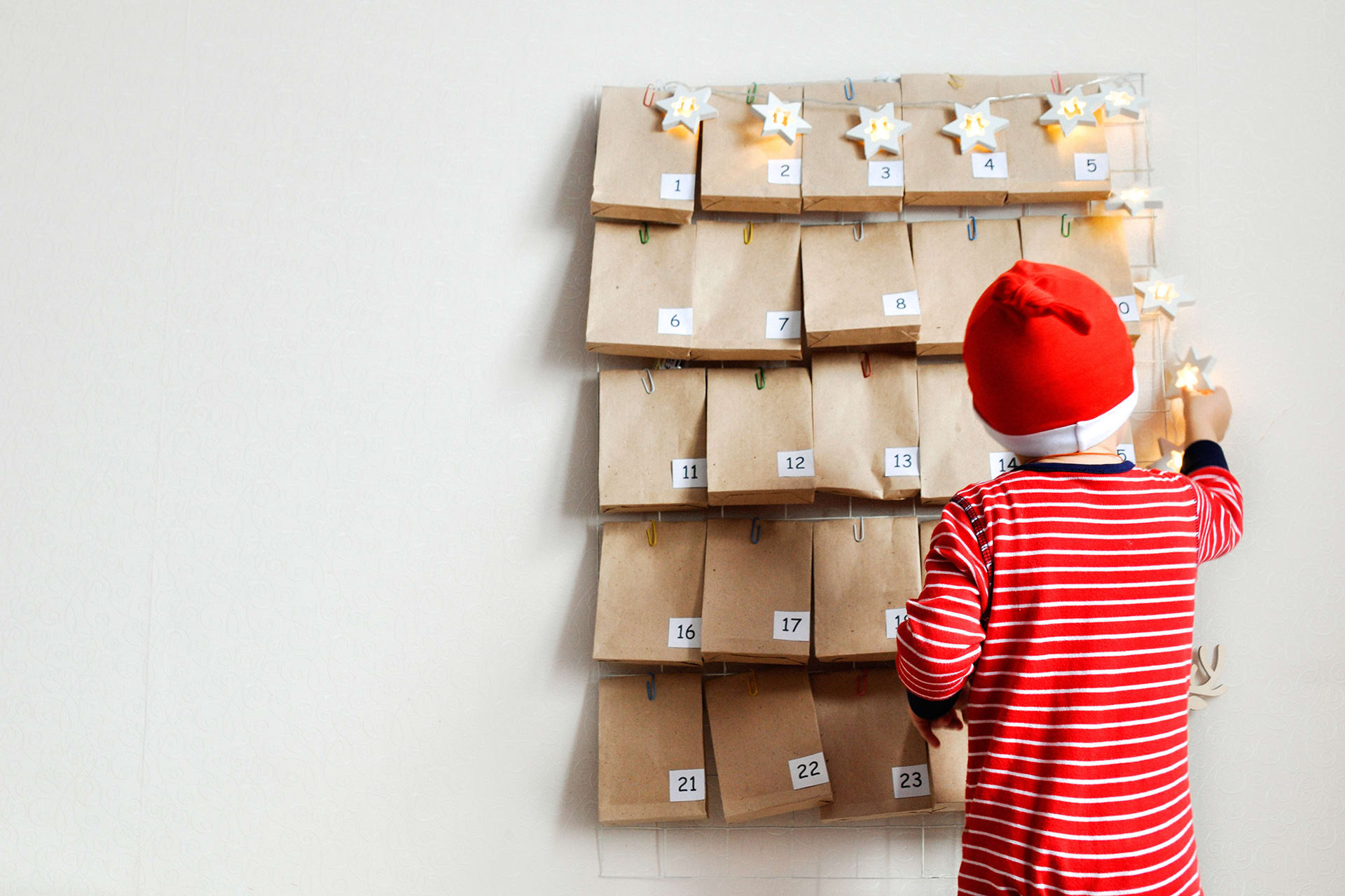 Adventskalender basteln | Kind steht mit Nikolausmütze vor dem Adventskalender