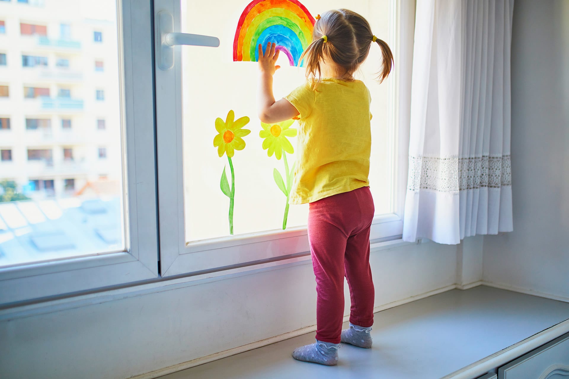  Fingerfarben-Ideen Kinder | Mädchen malt mit Fingern Regenbogen an ein Fenster