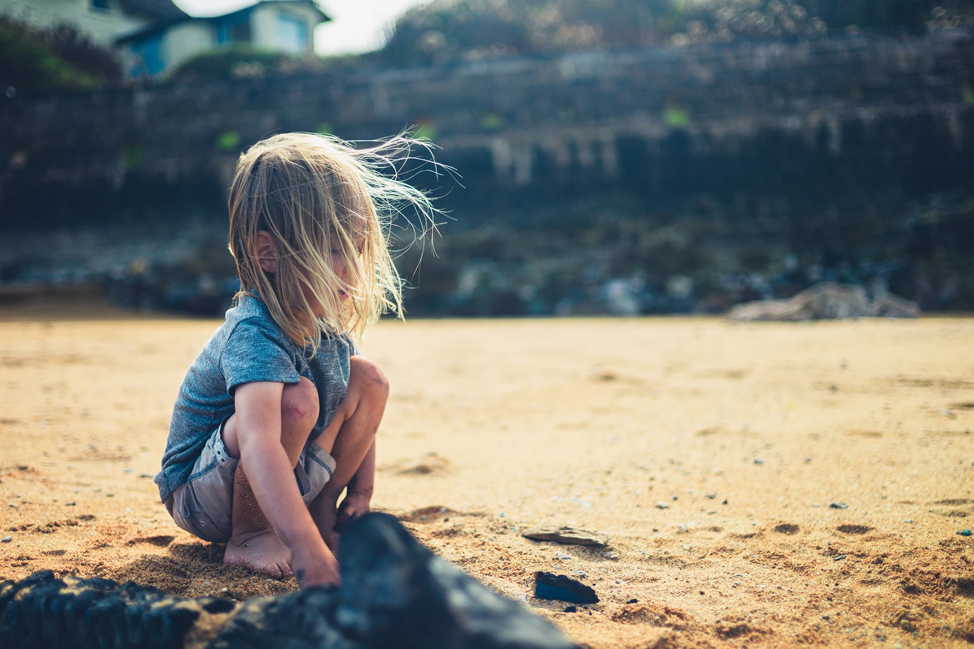 Flechtfrisuren | Kind sitzt in der Hocke am Strand