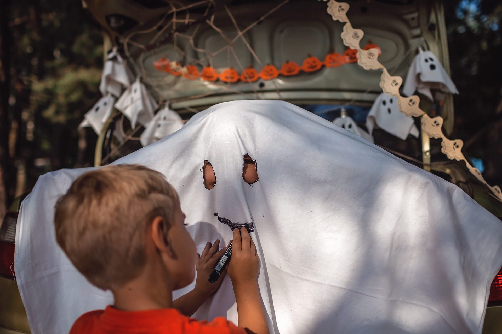 Halloween-Dekoration |  Kind steht vor einem als Gespenst verkleidet