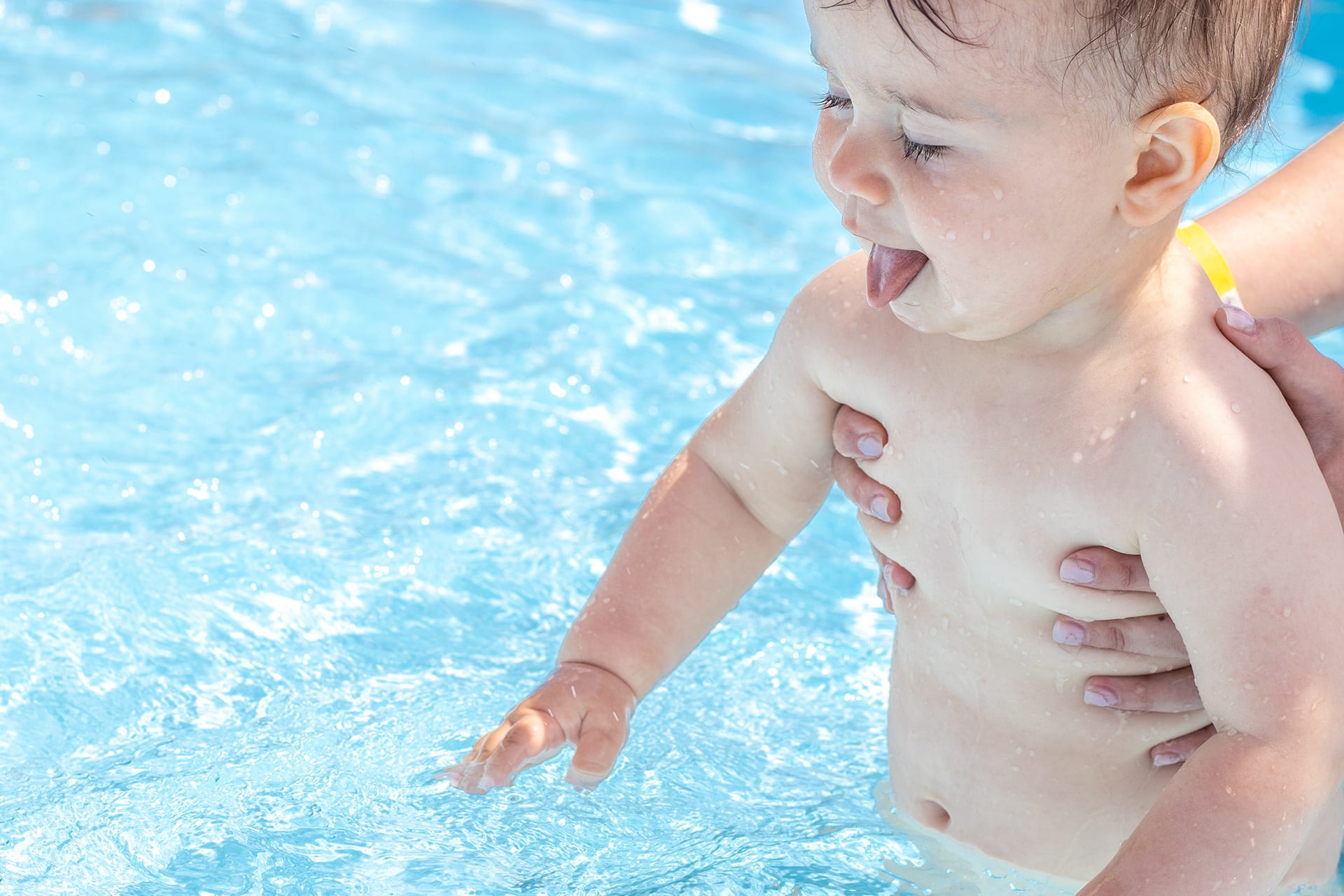  Frühkindliche Förderung | Baby wird ins Schwimmbecken gehalten 