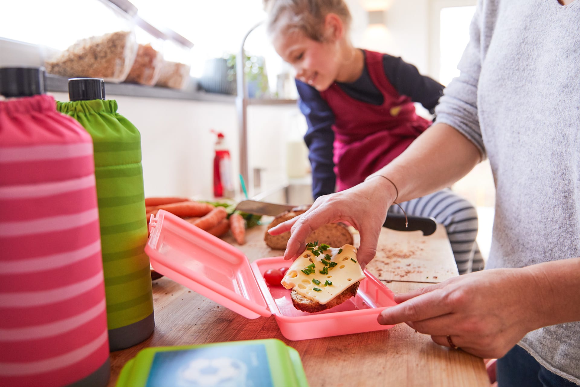  Ideen für Pausenbrote | rote Brotdose geöffnet und Kind nimmt sich Käsebrot