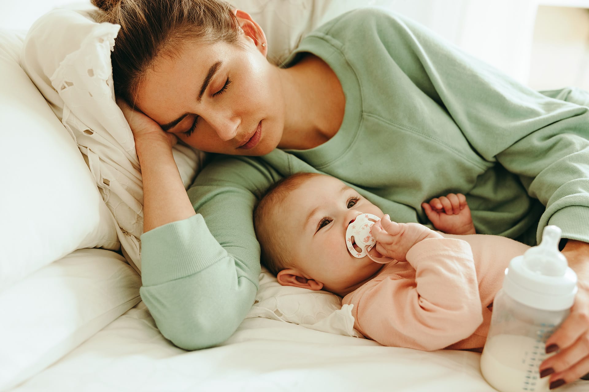 Baby im Herbst richtig anziehen | Mutter und Kind liegen auf Bett