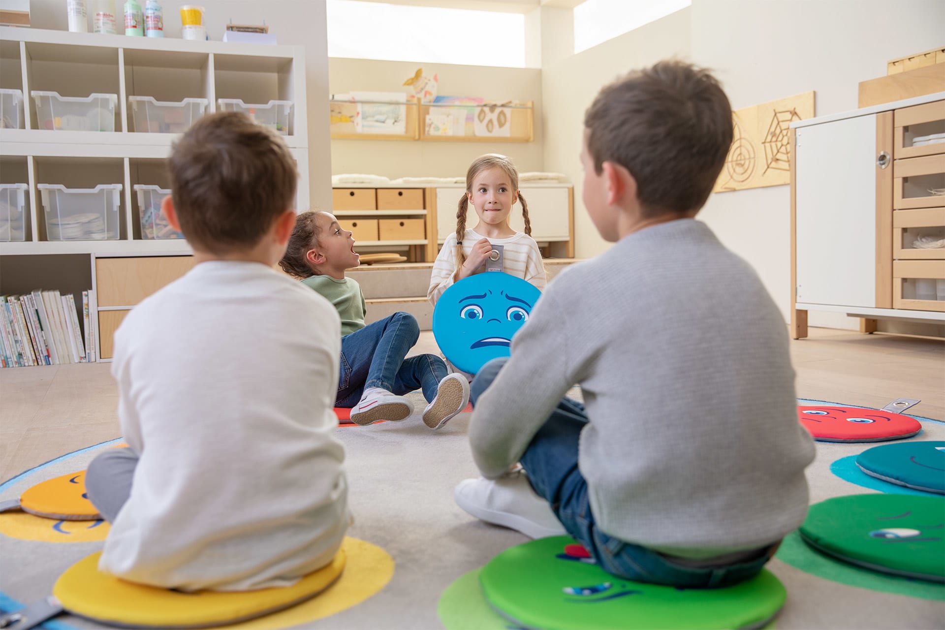 Emotionen | Kinder sitzen auf Emotionen Sitzkissen und unterhalten sich
