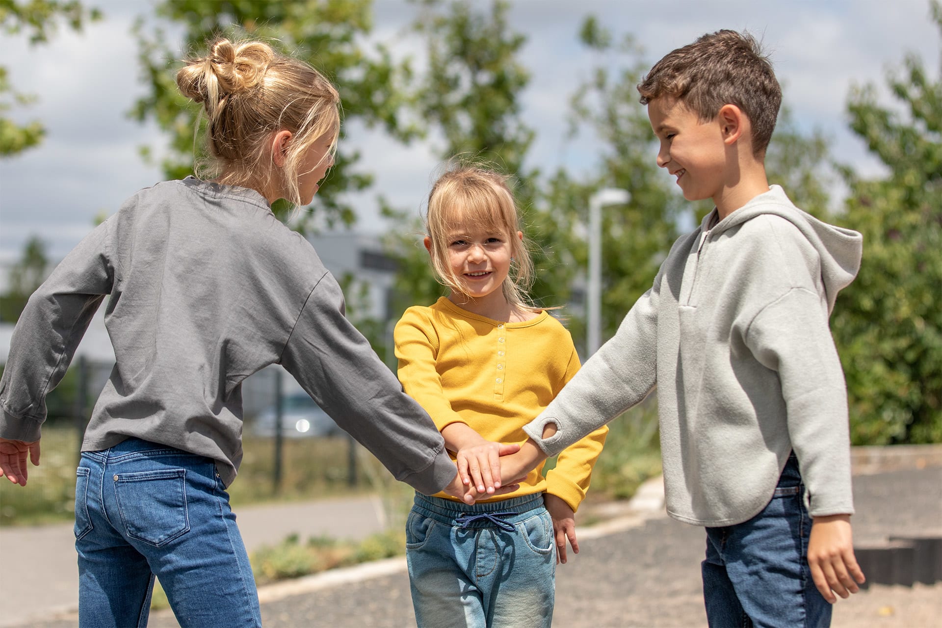 Teamfähigkeit | Image | 3 Kinder stehen in einem Kreis und halten ihre Hände übereinander