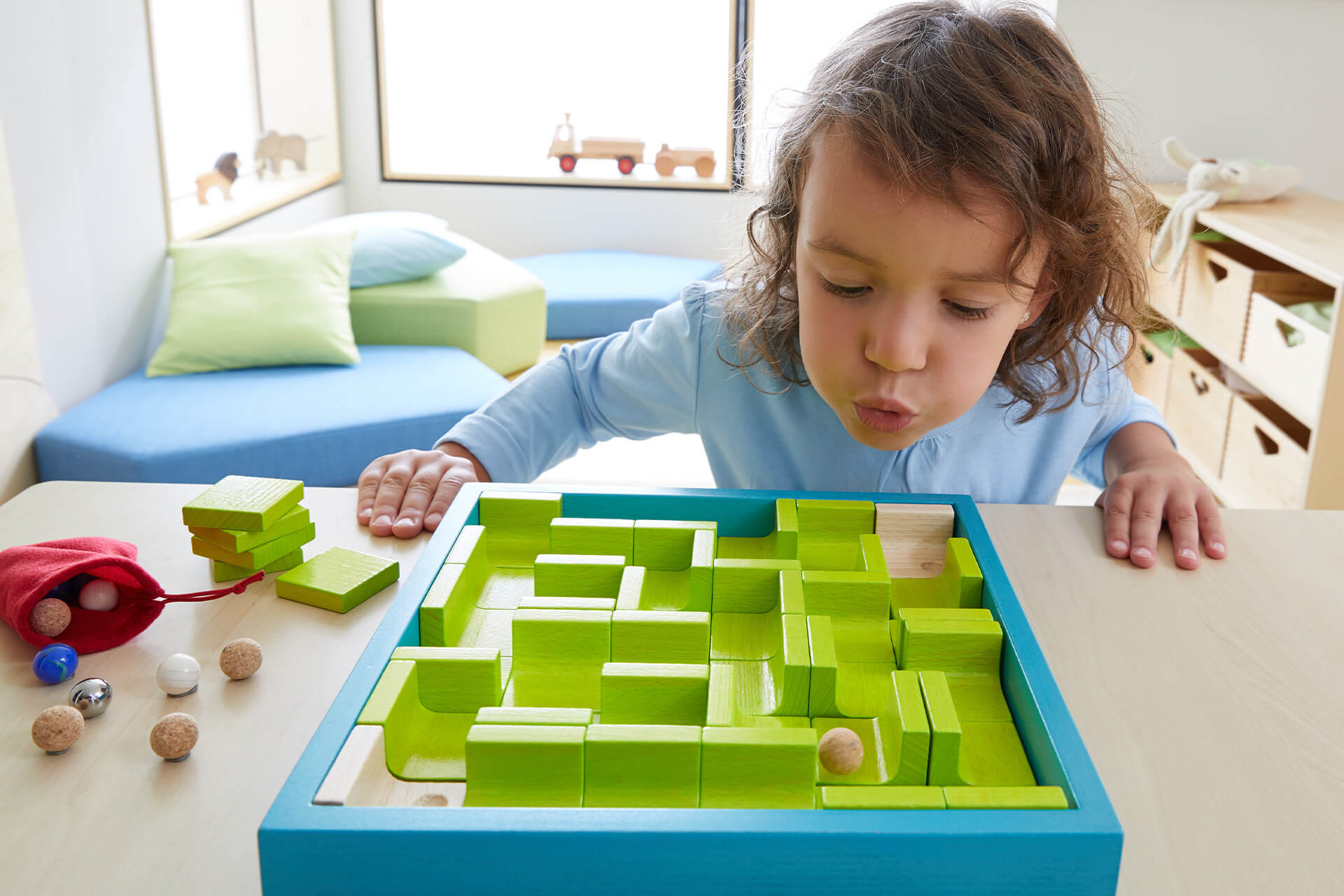 11 Sprachspiele für Kinder | 10. Sprachförderung mit Murmelspielen | Kind pustet in Holzkugel im Legelabyrinth