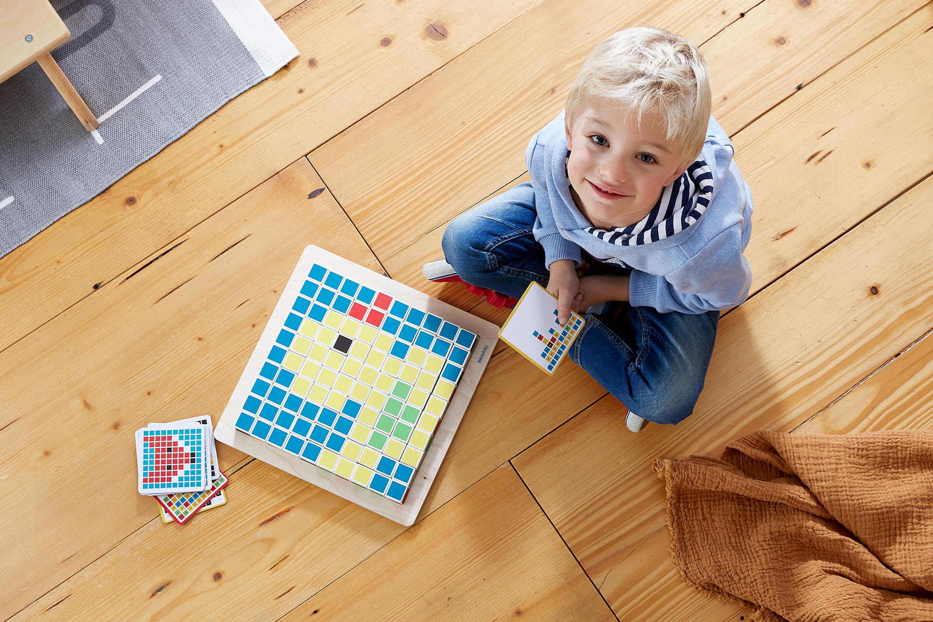 Digital Starter | Junge sitzt auf dem Boden und spielt das Legespiel Coding Pixel von Digital Starter