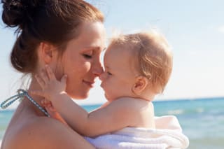 Reisen mit Baby und Kleinkind | Mutter genießt mit Baby am Strand