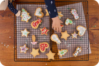 Backen für Kindergeburtstag | Kind legt fertige Plätzchen auf Rost