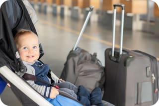 Fliegen mit Baby | Baby Junge sitzt im Kinderwagen in der Nähe von Gepäck