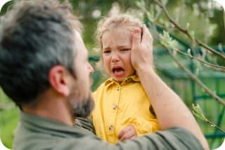  Berliner Modell | Vater hält seine weinende kleine Tochter und tröstet sie im Garten