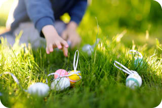 Ostern mit Kindern | Kind greift Osterei im Gras