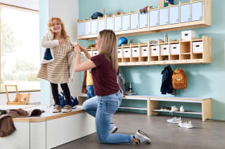 Garderobe | Image | Mutter kniet auf den Boden und zieht Kind aus 