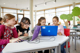 Digitalwerkstatt | Viele Kinder sitzen mit Apple Laptops am Tisch in einem Workshop
