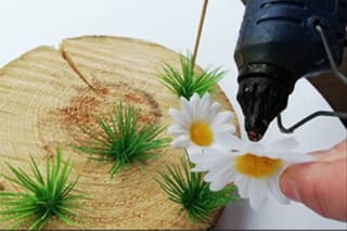 DIY-Anleitung: Hochzeitsgeschenk | Blumen und Gräser werden mit Klebepistole auf Baumscheibe geklebt