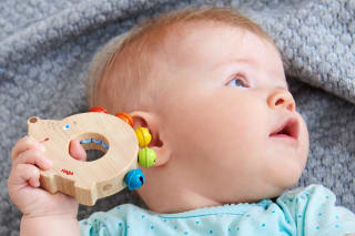 Sinneswahrnehmung bei Kindern | Baby hält Holzring mit Rassel von HABA ans Ohr