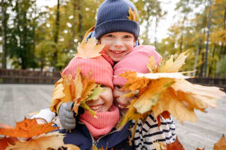  Herbstspiele mit Kindern | Kinder mit Blättern in der Hand