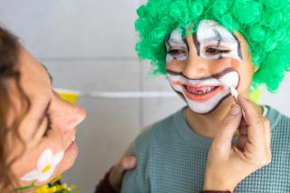 Faschings schminken | Image | Kind mit grüner Clownsperücke wird im Gesicht als Clown geschminkt