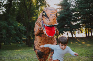 Rollenspiele | Vater und Sohn spielen im Park, mit einem Dinosaurier-Kostüm, 