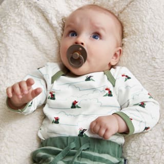 Schnuller abgewöhnen |  Image | Baby liegt auf Kissen und hat einen braunen Schnuller im Mund