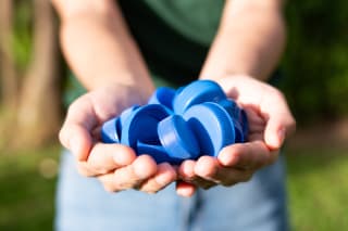 Kinderspiele selber machen | Kind hält Plastik-Schraub-Verschlüsse in Händen