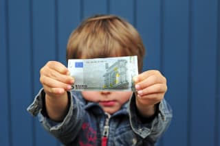 Wie viel Taschengeld | Junge hält 5 Euro Schein hoch