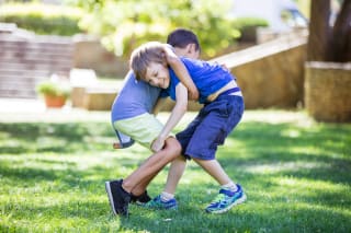 Aggressives Verhalten bei Kindern | Zwei Jungen kämpfen im Freien. Geschwister oder Freunde ringen im Park