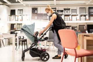 Einkaufen mit Baby | Mutter schiebt Buggy und schaut ihr Kind an