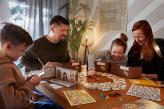 Familienzusammenhalt | Familie spielt ein Spiel am Wohnzimmertisch